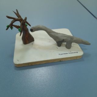 Динозавр ест листья с дерева.